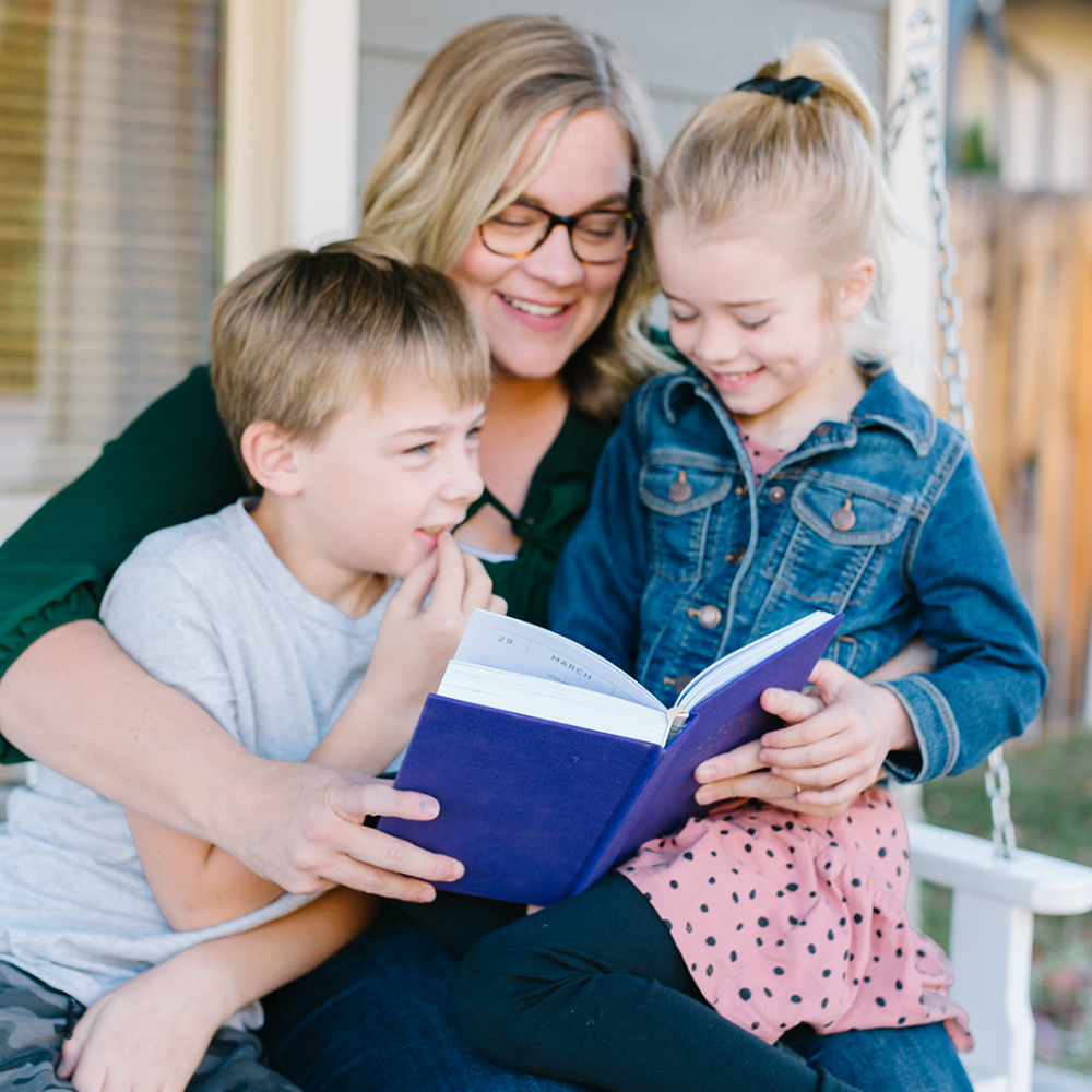 Rachel Nielson, host of the 3 in 30 Takeaways for Moms Podcast, and her two children hold a Flecks of Gold Journal- a 3 year journal for moms. This journal helps moms who are overwhelmed see the beauty, magic, and gold in their everyday moments.