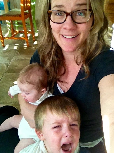 Rachel Nielson, host of the 3 in 30 Takeaways for Moms Podcast, holds a screaming toddler and baby.  She understands what it feels like to be overwhelmed.