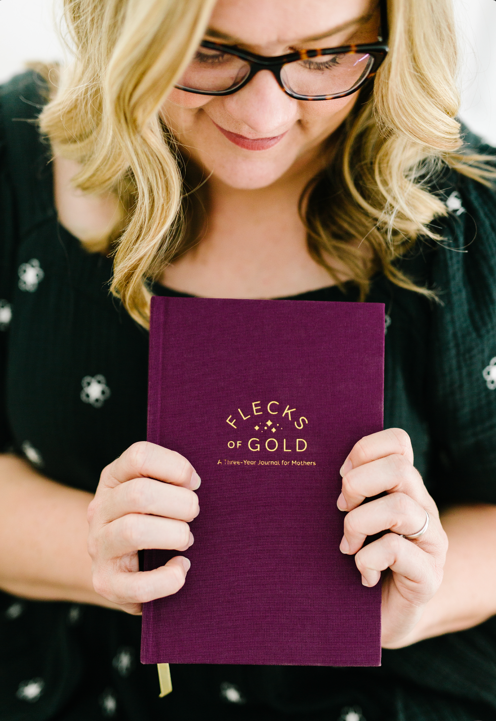 Rachel Nielson, host of the 3 in 30 Takeaways for Moms Podcast, holds a Flecks of Gold Journal- a 3 year journal for moms.  This journal helps moms who are overwhelmed see the beauty, magic, and gold in their everyday moments.