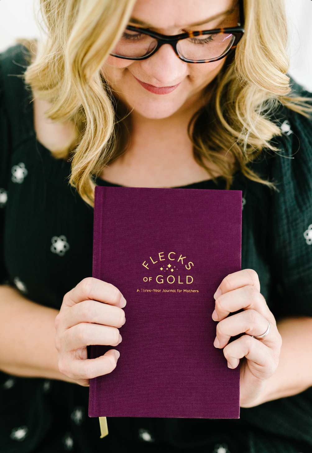 Rachel Nielson, host of the 3 in 30 Takeaways for Moms Podcast, holds a Flecks of Gold Journal- a 3 year journal for moms. This journal helps moms who are overwhelmed see the beauty, magic, and gold in their everyday moments.