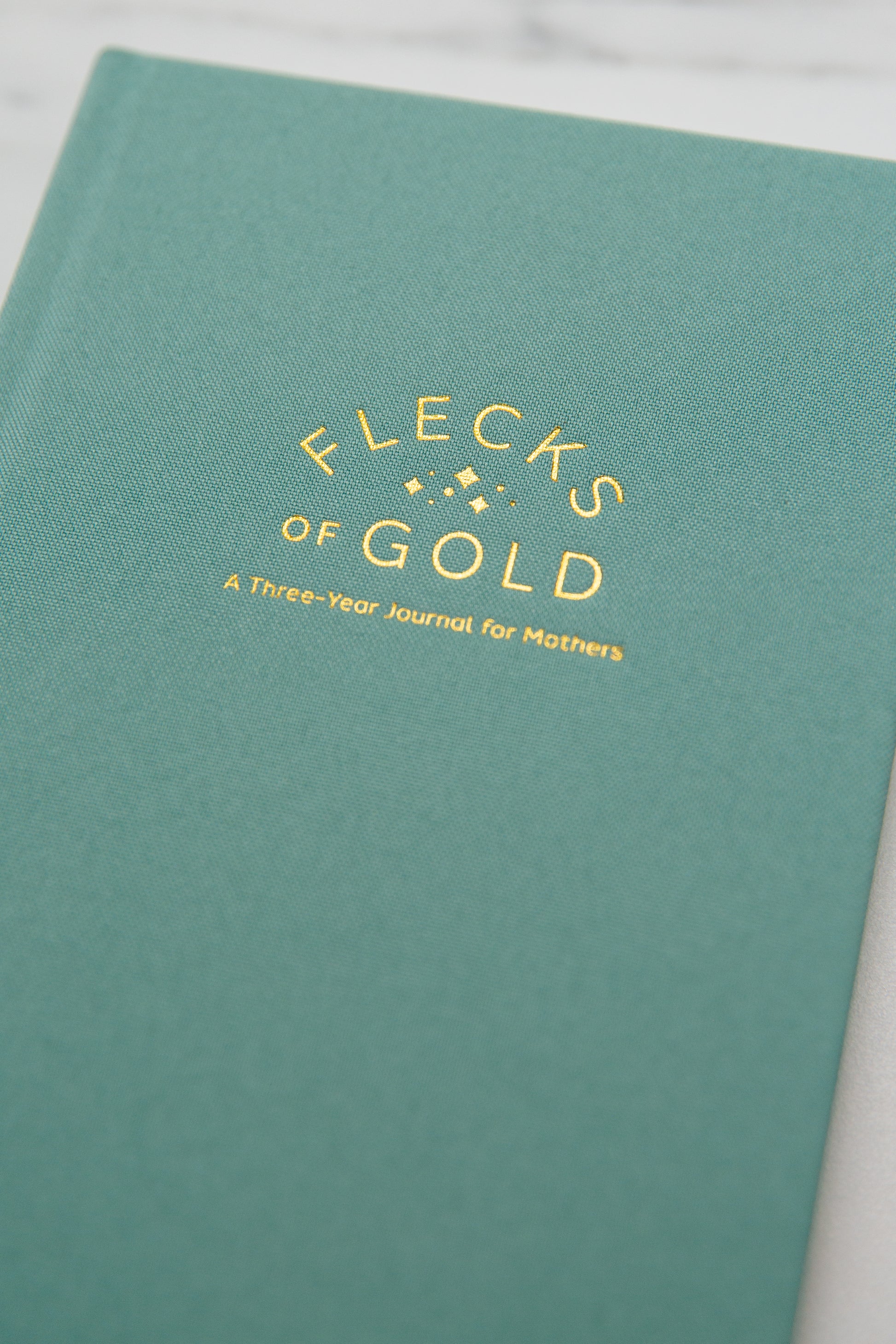 Teal Linen Flecks of Gold Journal with gold embossing. A Three-Year Journal For Mothers. Helping you find the joy in Motherhood. A journal for moms who want to see the good in every day. Helping overwhelmed, busy moms. Created by Rachel Nielson of 3 in 30 Podcast.  Motherhood Journal.  Three-year journal. Gratitude Journal.