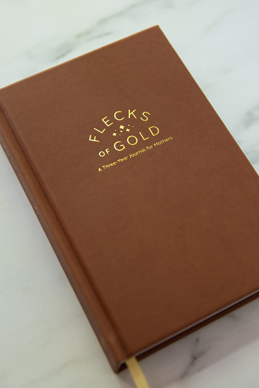 Camel vegan leather Flecks of Gold journal at an angle, showing the gold-foil cover title
